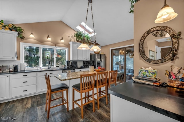 kitchen with dark countertops, dark wood-style floors, stainless steel appliances, and tasteful backsplash