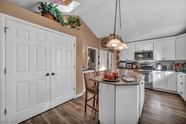 kitchen featuring a center island, vaulted ceiling with skylight, white cabinets, and stainless steel appliances