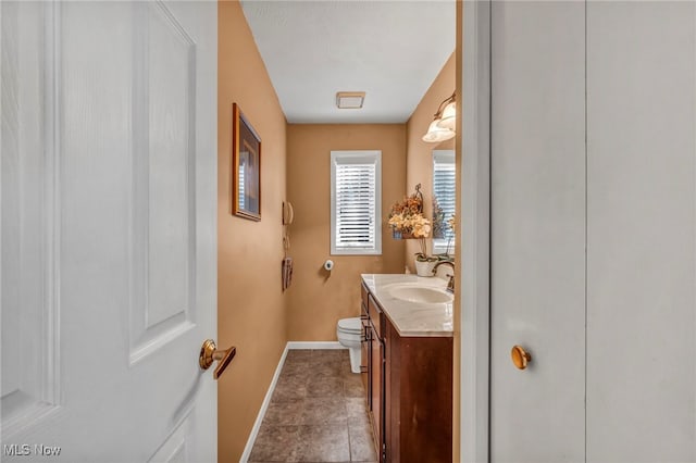 bathroom with tile patterned flooring, toilet, vanity, and baseboards