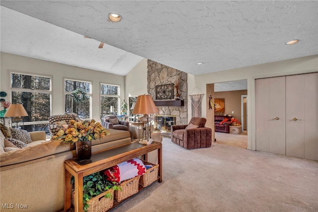 living area with carpet floors, a textured ceiling, a stone fireplace, and vaulted ceiling