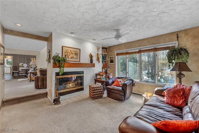 carpeted living room featuring a fireplace with flush hearth and ceiling fan