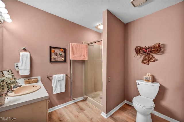 full bath featuring a shower stall, toilet, vanity, and wood finished floors