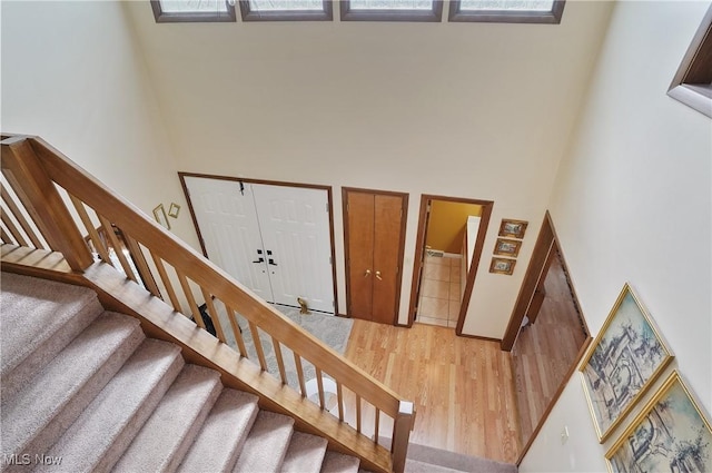 stairs featuring wood finished floors and a towering ceiling