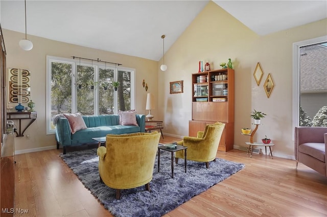 living area featuring light wood-type flooring, baseboards, and high vaulted ceiling