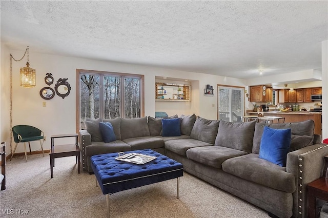 living area featuring light carpet, a textured ceiling, and baseboards