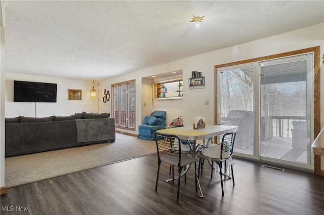 dining room featuring visible vents, a textured ceiling, and dark wood-style flooring