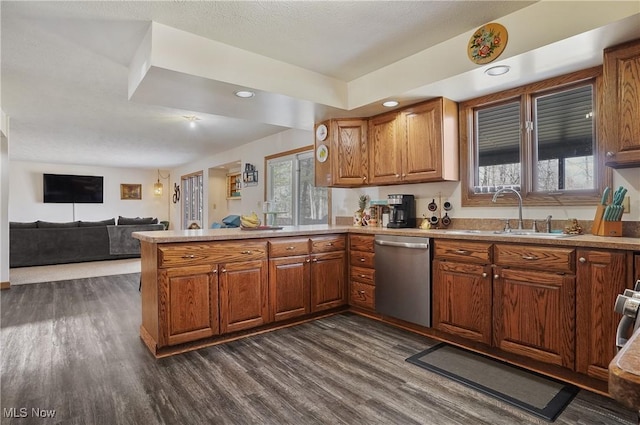 kitchen with dark wood-style flooring, brown cabinets, a peninsula, stainless steel dishwasher, and a sink