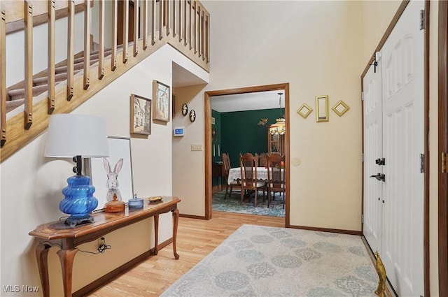 entryway with stairway, light wood-style flooring, baseboards, and a towering ceiling