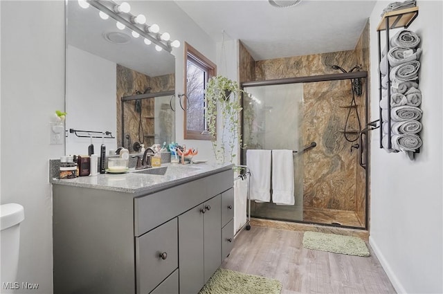 bathroom with vanity, wood finished floors, a shower stall, and toilet