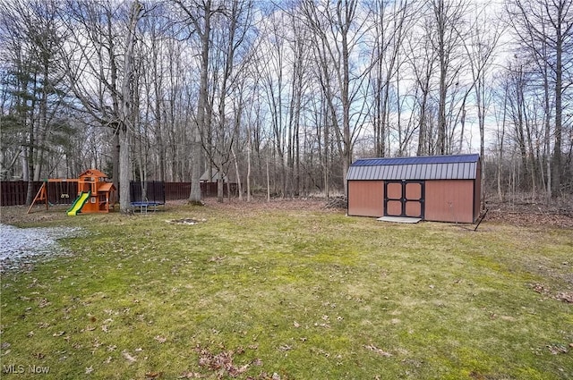 view of yard featuring an outbuilding, a trampoline, fence, a shed, and a playground