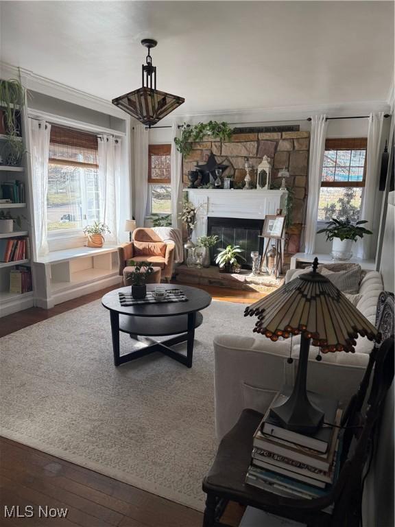 living area featuring a wealth of natural light, a glass covered fireplace, and hardwood / wood-style floors