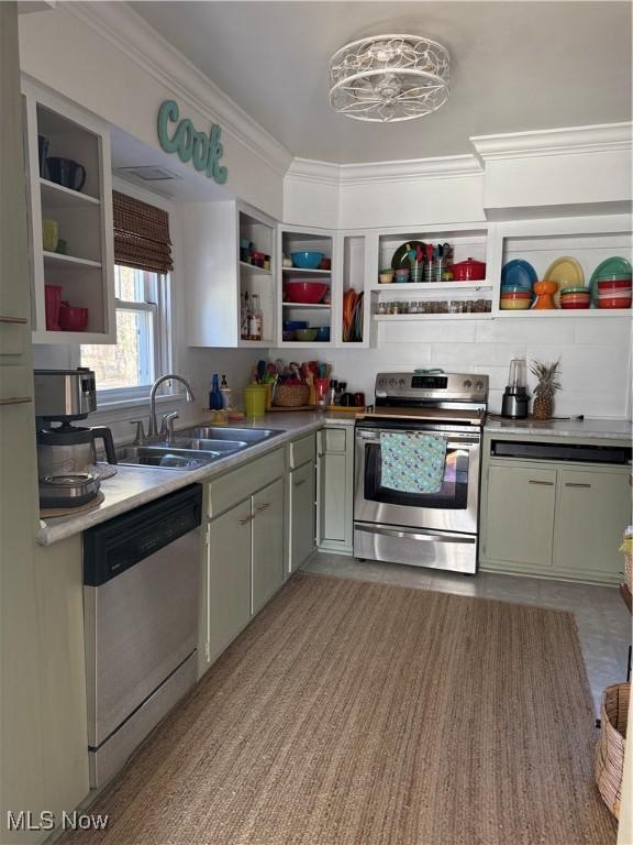 kitchen with open shelves, crown molding, light countertops, appliances with stainless steel finishes, and a sink