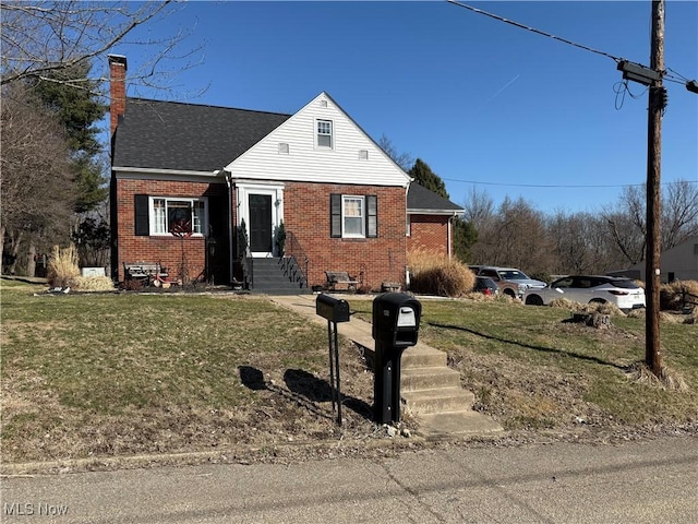 view of front of home featuring a shingled roof, a front yard, brick siding, and a chimney