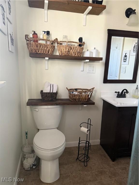 bathroom with tile patterned flooring, toilet, vanity, and baseboards