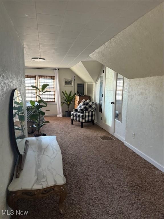 sitting room featuring visible vents, baseboards, carpet flooring, and vaulted ceiling