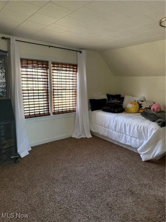 unfurnished bedroom featuring baseboards, lofted ceiling, and carpet flooring