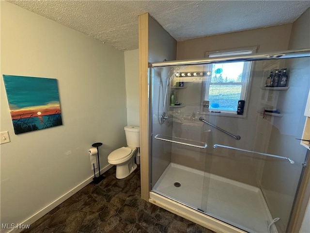 bathroom featuring baseboards, toilet, a shower stall, and a textured ceiling