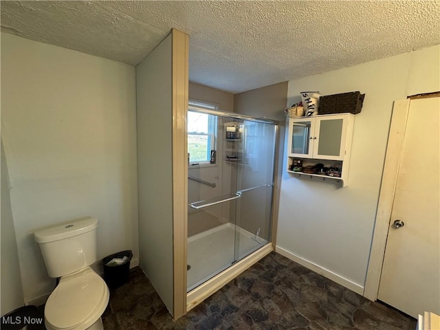 bathroom with a stall shower, toilet, and a textured ceiling