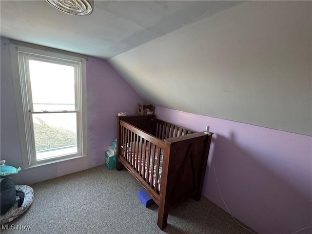 bedroom with carpet flooring, a crib, and lofted ceiling