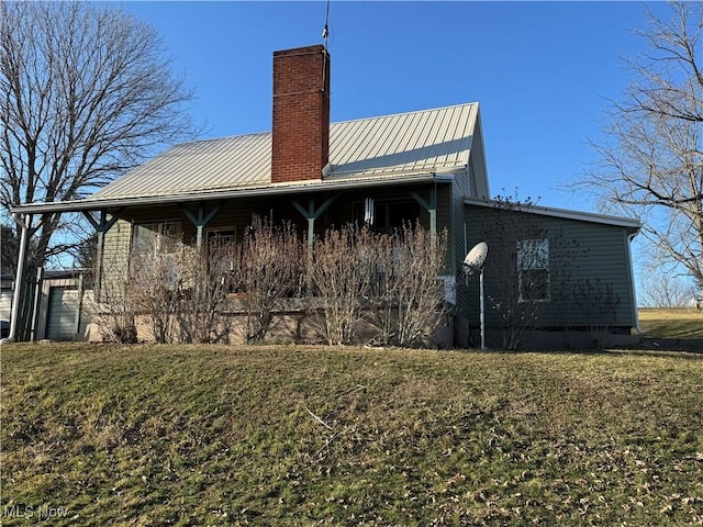 rear view of house with a yard, metal roof, and a chimney