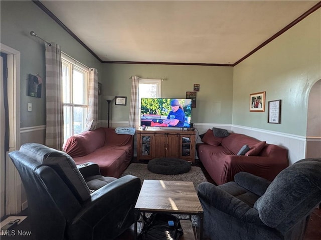 living room with a wainscoted wall, arched walkways, and ornamental molding