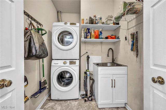 clothes washing area with cabinet space, stacked washer / drying machine, and a sink