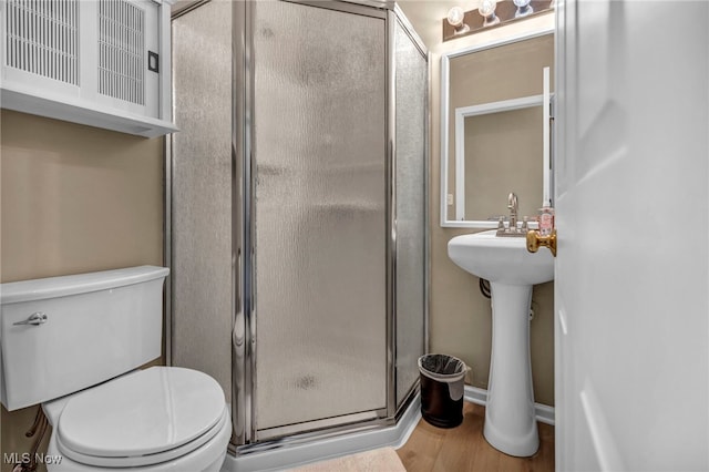 full bathroom featuring toilet, wood finished floors, and a stall shower