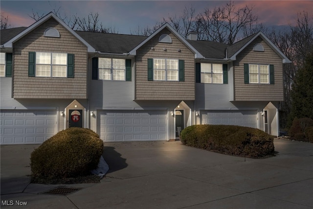 view of front facade featuring driveway, a chimney, and a garage