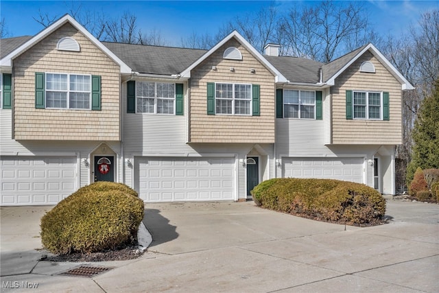 multi unit property featuring an attached garage, driveway, and a chimney