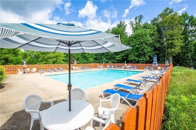 community pool with outdoor dining area, a patio area, and fence