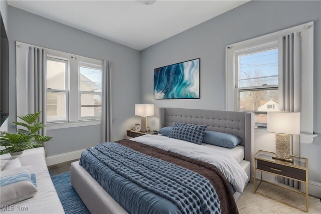 bedroom with baseboards, multiple windows, and wood finished floors