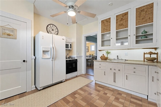 kitchen featuring a sink, range, white refrigerator with ice dispenser, and light countertops