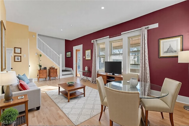 dining space with recessed lighting, an accent wall, light wood-style flooring, and stairs