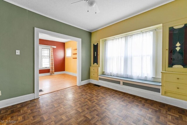 unfurnished room featuring a textured ceiling, visible vents, baseboards, and ceiling fan