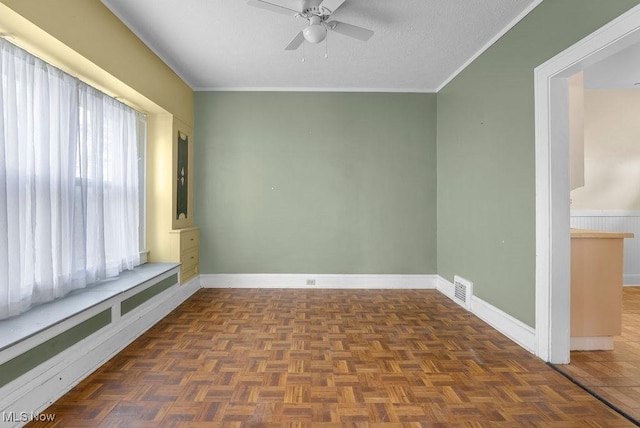 spare room with a textured ceiling, baseboards, visible vents, and ornamental molding