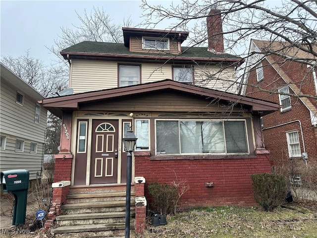 traditional style home featuring brick siding, entry steps, and a chimney