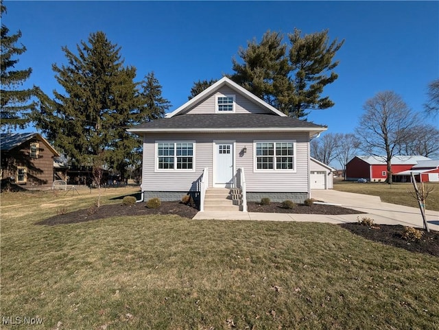 bungalow with an outbuilding, a garage, a front yard, and roof with shingles