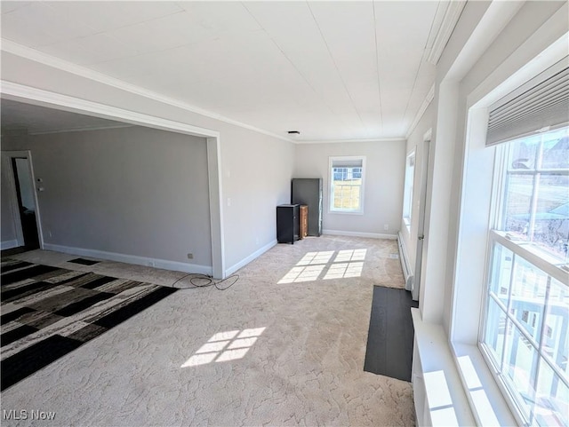 unfurnished living room featuring baseboards, ornamental molding, and carpet flooring