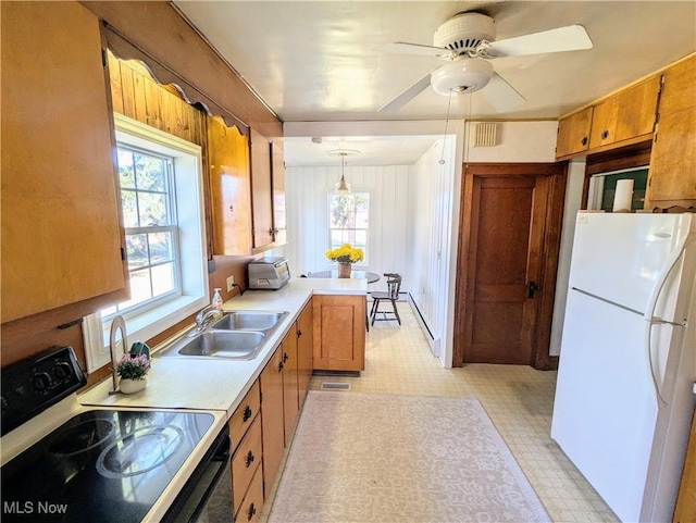 kitchen with light floors, light countertops, freestanding refrigerator, electric stove, and a sink