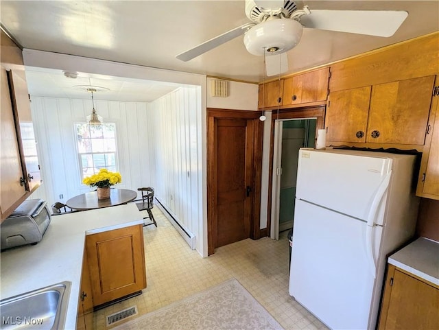 kitchen with brown cabinetry, freestanding refrigerator, and a baseboard radiator