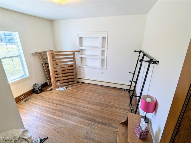 interior space featuring wood-type flooring, baseboards, visible vents, and baseboard heating