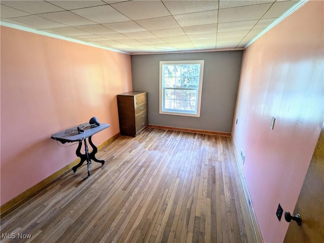 interior space featuring a paneled ceiling, baseboards, crown molding, and hardwood / wood-style flooring