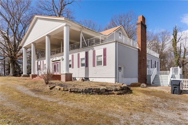 view of side of home featuring french doors, a balcony, and a chimney