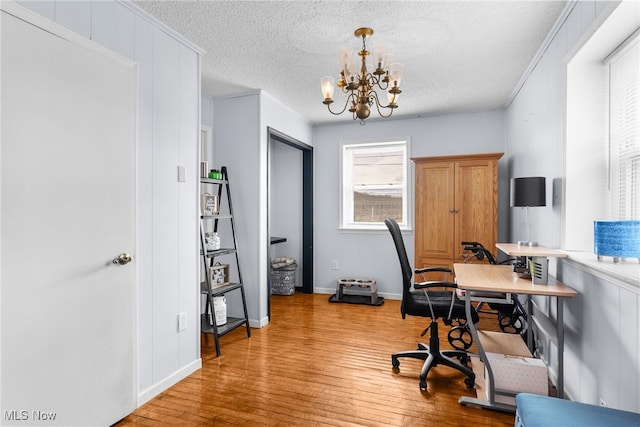 office space featuring light wood finished floors, crown molding, baseboards, a chandelier, and a textured ceiling