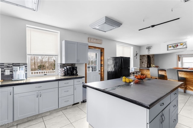 kitchen with dark countertops, plenty of natural light, and freestanding refrigerator