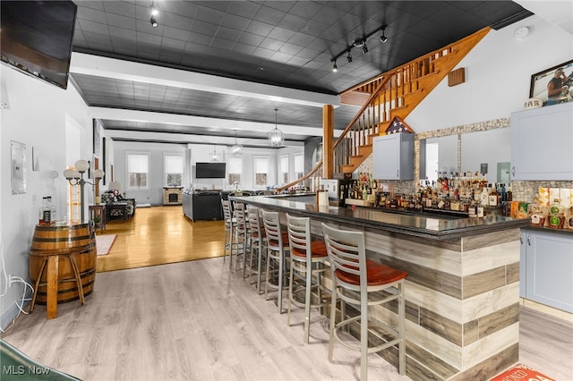 bar featuring a dry bar, stairway, light wood-style flooring, and backsplash