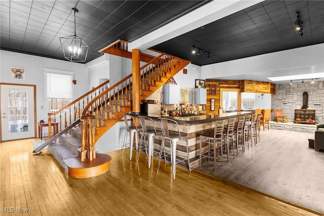 bar with stairway, a dry bar, a wood stove, and wood-type flooring