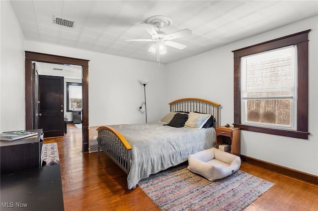 bedroom with hardwood / wood-style flooring, baseboards, visible vents, and ceiling fan