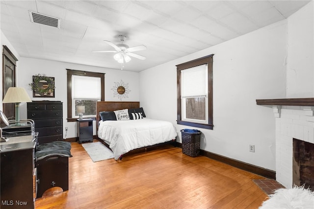 bedroom featuring visible vents, a fireplace, baseboards, and wood finished floors