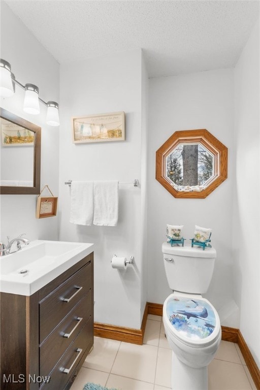 half bath featuring toilet, a textured ceiling, tile patterned flooring, baseboards, and vanity